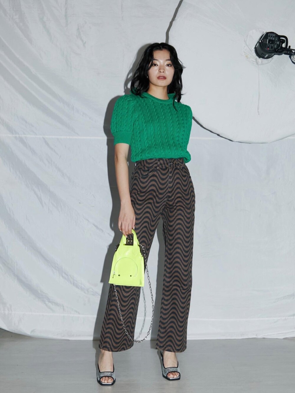 グリーン系のニット/セーター、イエロー系のショルダーバッグ、シルバー系のサンダルを着用したレディースの春コーディネートの2枚目の写真