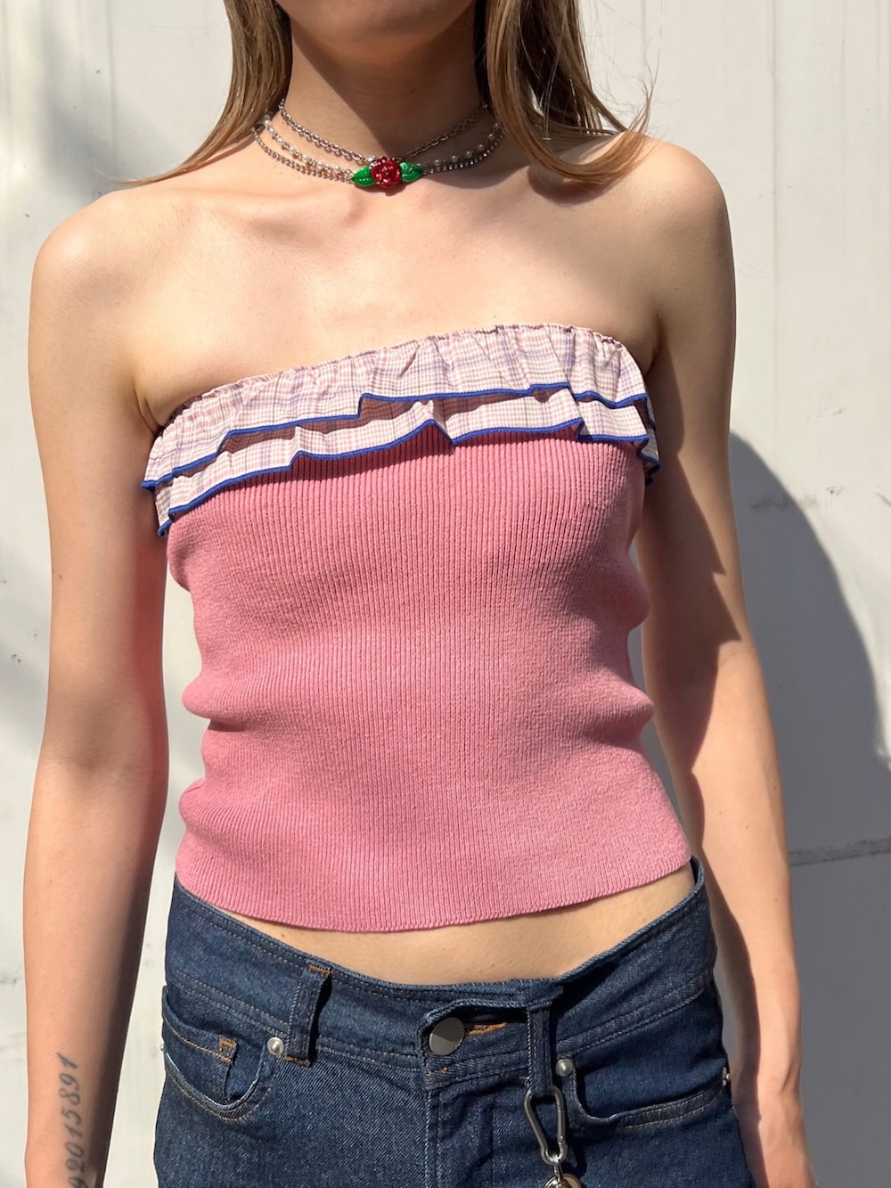 ピンク系のチューブトップ、ブラック系のデニムパンツ、シルバー系のサンダルを着用したレディースの夏コーディネートの2枚目の写真