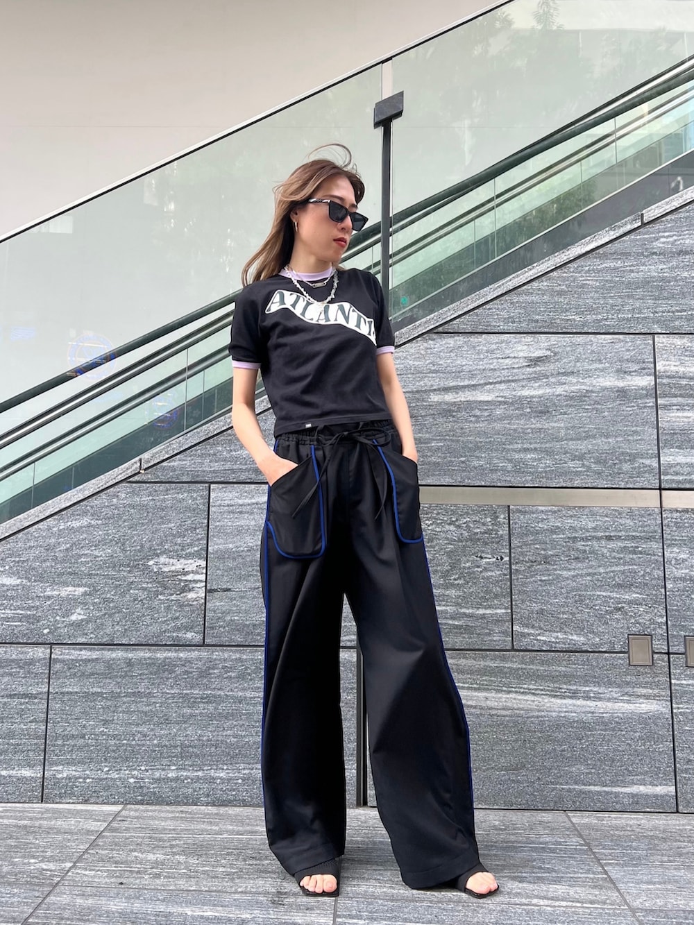 ブラック系のスラックス、ブラック系のTシャツ/カットソー、ブラック系のサンダルを着用したレディースの夏コーディネートの2枚目の写真