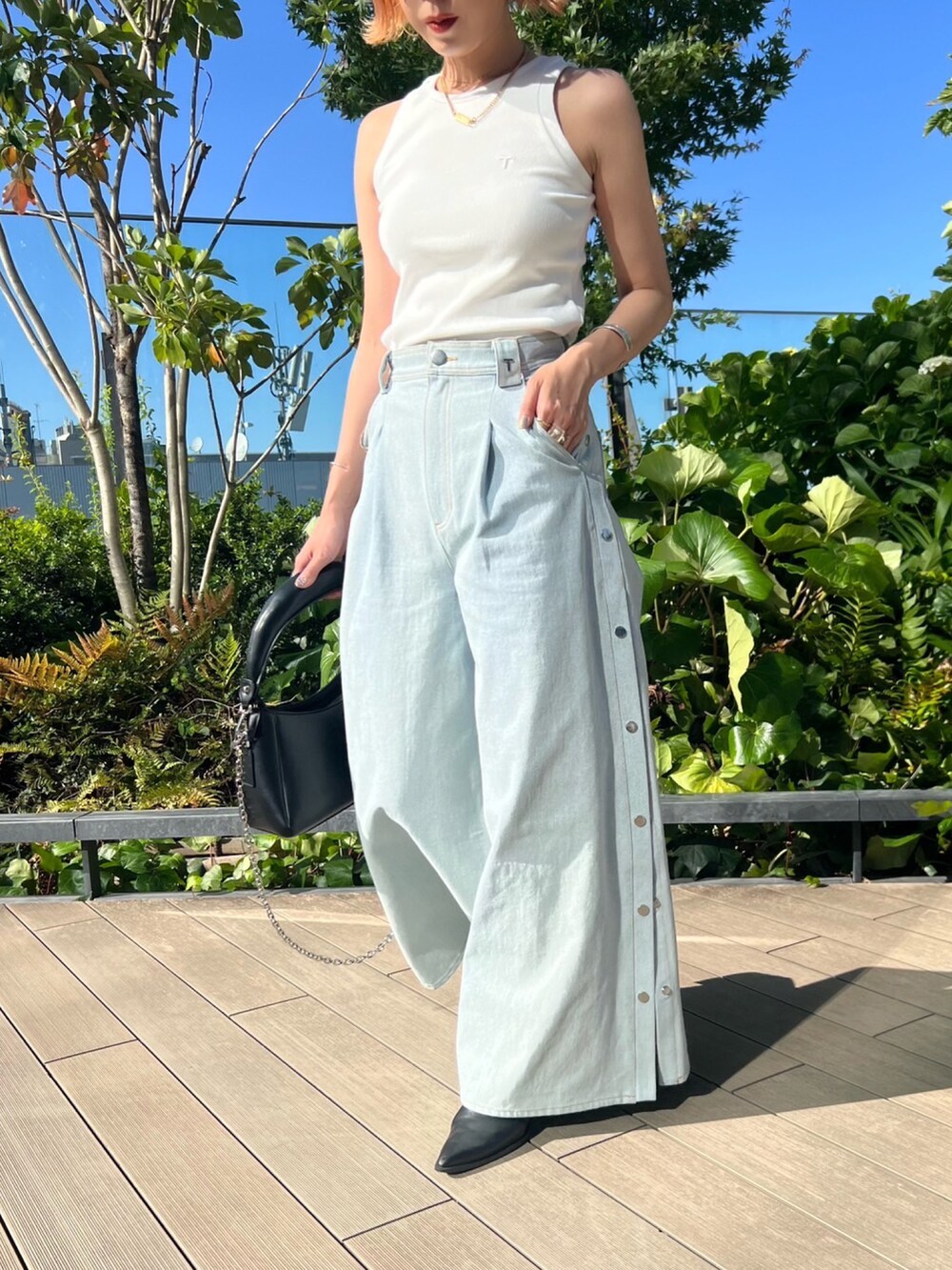 ブラック系のハンドバッグ、ブルー系のデニムパンツ、ホワイト系のタンクトップを着用したレディースの春コーディネートの2枚目の写真