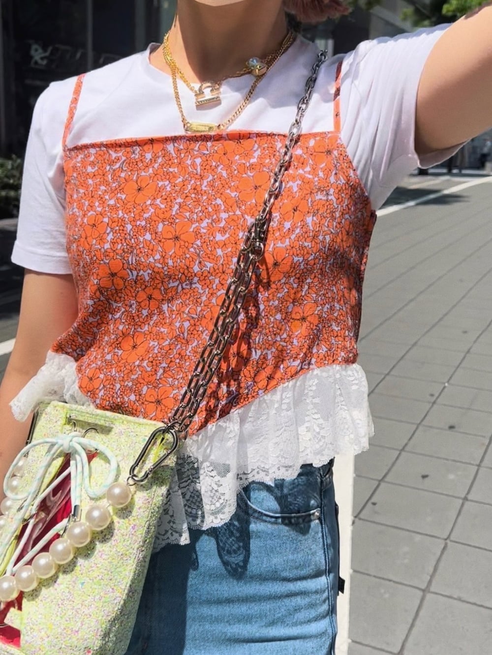オレンジ系のキャミソール、その他のトートバッグ、ブルー系のデニムパンツを着用したレディースの夏コーディネートの3枚目の写真