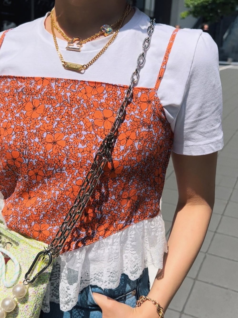 オレンジ系のキャミソール、その他のトートバッグ、ブルー系のデニムパンツを着用したレディースの夏コーディネートの4枚目の写真