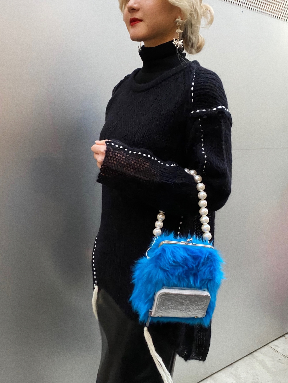 ブラック系のニット/セーター、ブラック系のスカート、ブルー系のショルダーバッグを着用したレディースの冬コーディネートの2枚目の写真