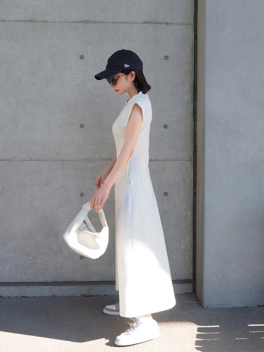 グレー系のワンピース、グレー系のスニーカー、ホワイト系のハンドバッグを着用したレディースの夏コーディネートの2枚目の写真