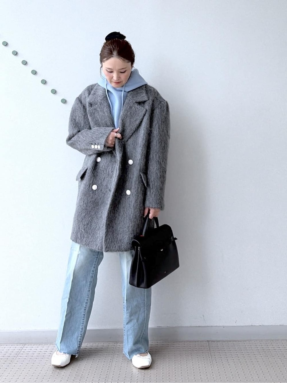 ブルー系のニット/セーター、ブルー系のデニムパンツ、ブラック系のボストンバッグを着用したレディースの冬コーディネートの6枚目の写真