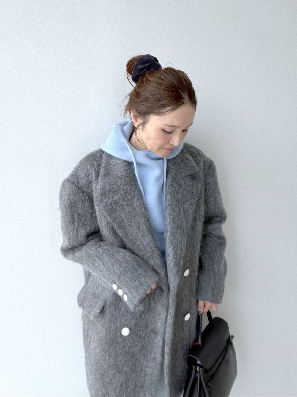 ブルー系のニット/セーター、ブルー系のデニムパンツ、ブラック系のボストンバッグを着用したレディースの冬コーディネートの5枚目の写真