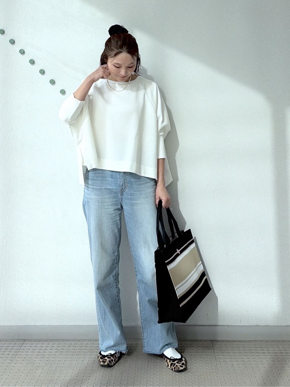 ホワイト系のTシャツ/カットソー、ブルー系のデニムパンツ、ブラック系のトートバッグを着用したレディースの冬コーディネートの2枚目の写真