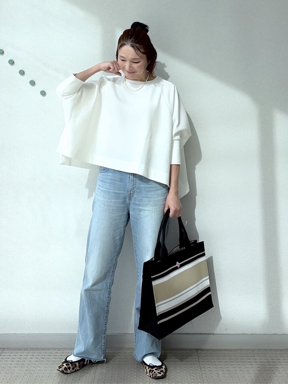 ホワイト系のTシャツ/カットソー、ブルー系のデニムパンツ、ブラック系のトートバッグを着用したレディースの冬コーディネートの3枚目の写真