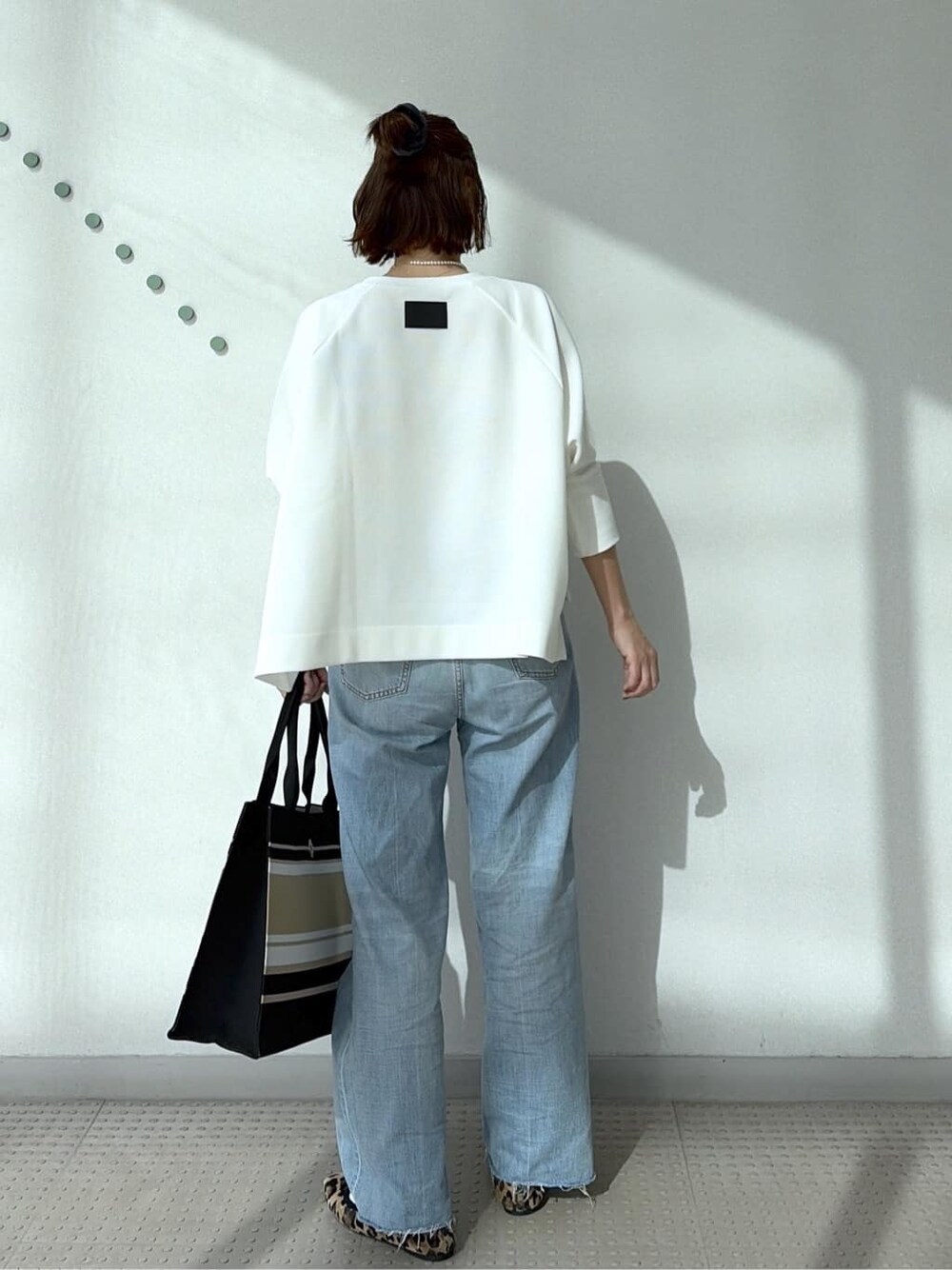 ホワイト系のTシャツ/カットソー、ブルー系のデニムパンツ、ブラック系のトートバッグを着用したレディースの冬コーディネートの6枚目の写真