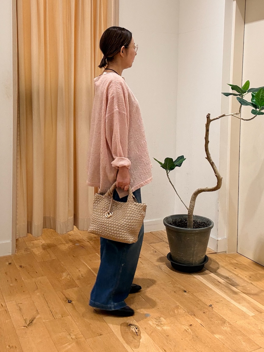 ブラック系のローファー、ブルー系のデニムパンツ、ベージュ系のハンドバッグを着用したレディースの秋コーディネートの2枚目の写真
