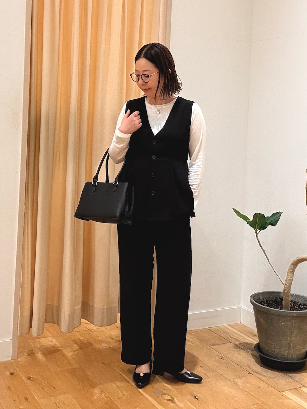 ブラック系のセットアップ、ホワイト系のTシャツ/カットソー、ブラック系のパンプスを着用したレディースの秋コーディネートの3枚目の写真