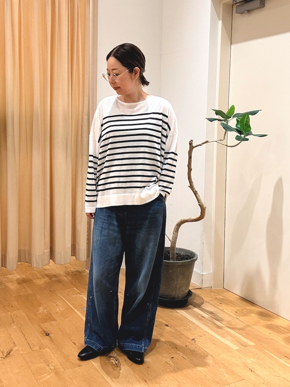 グレー系のワンピース、ブルー系のデニムパンツ、ブラウン系のショルダーバッグを着用したレディースの秋コーディネートの5枚目の写真