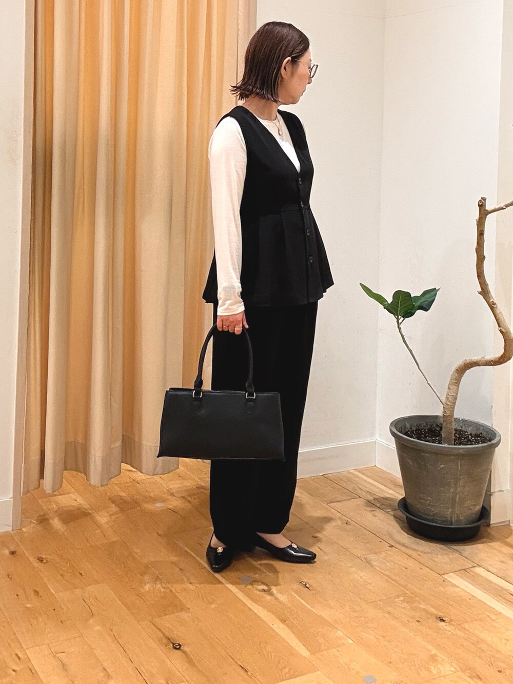 ブラック系のセットアップ、ホワイト系のTシャツ/カットソー、ブラック系のパンプスを着用したレディースの秋コーディネートの2枚目の写真