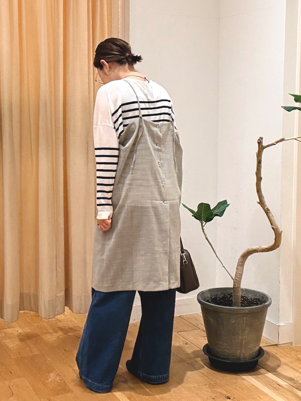 グレー系のワンピース、ブルー系のデニムパンツ、ブラウン系のショルダーバッグを着用したレディースの秋コーディネートの3枚目の写真
