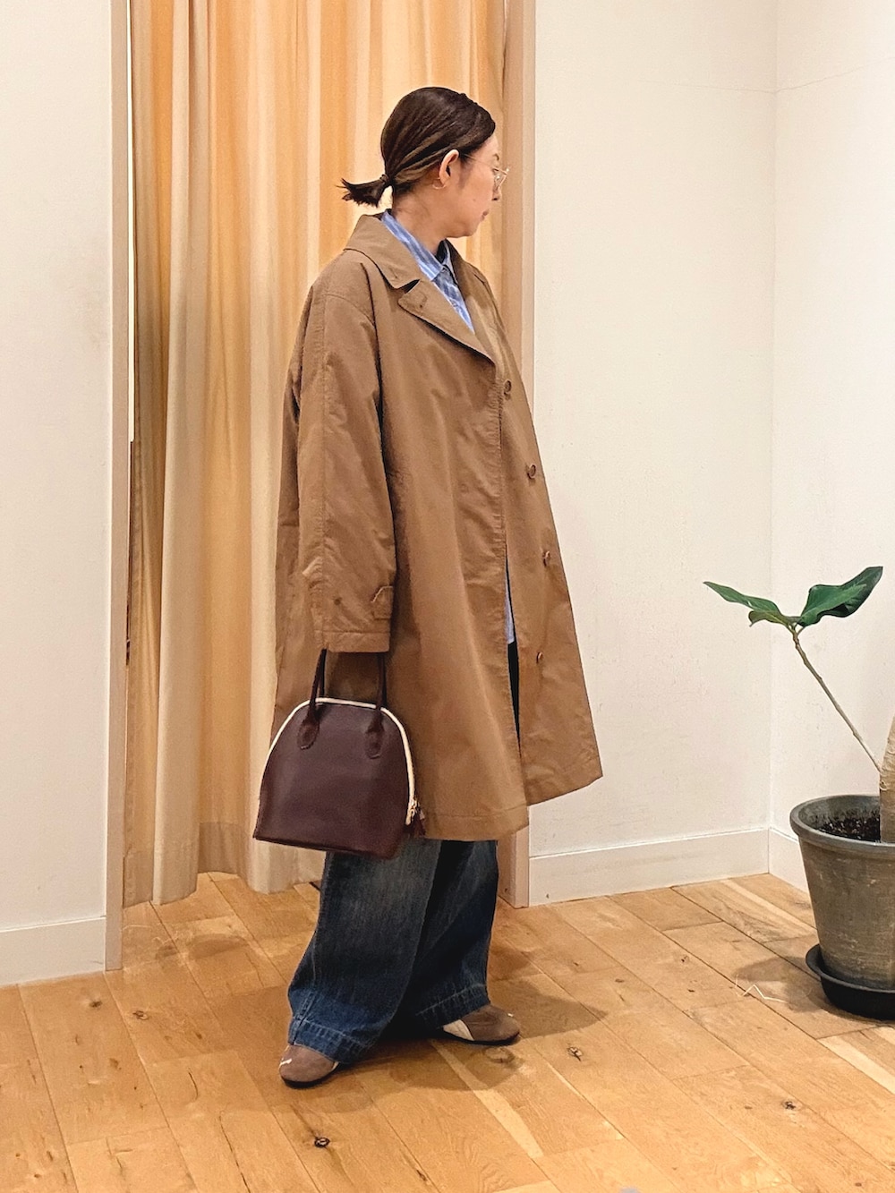 レッド系のハンドバッグ、ブルー系のシャツ/ブラウス、ブルー系のデニムパンツを着用したレディースの秋コーディネートの3枚目の写真