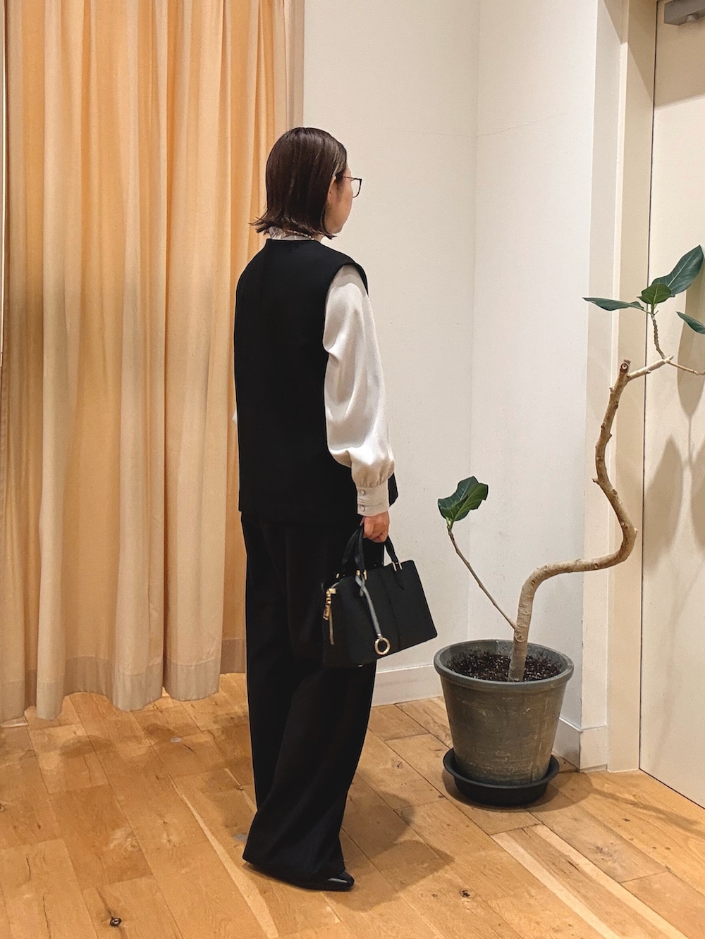 ブラック系のパンプス、ブラック系のハンドバッグ、ブラック系のベストを着用したレディースの秋コーディネートの3枚目の写真