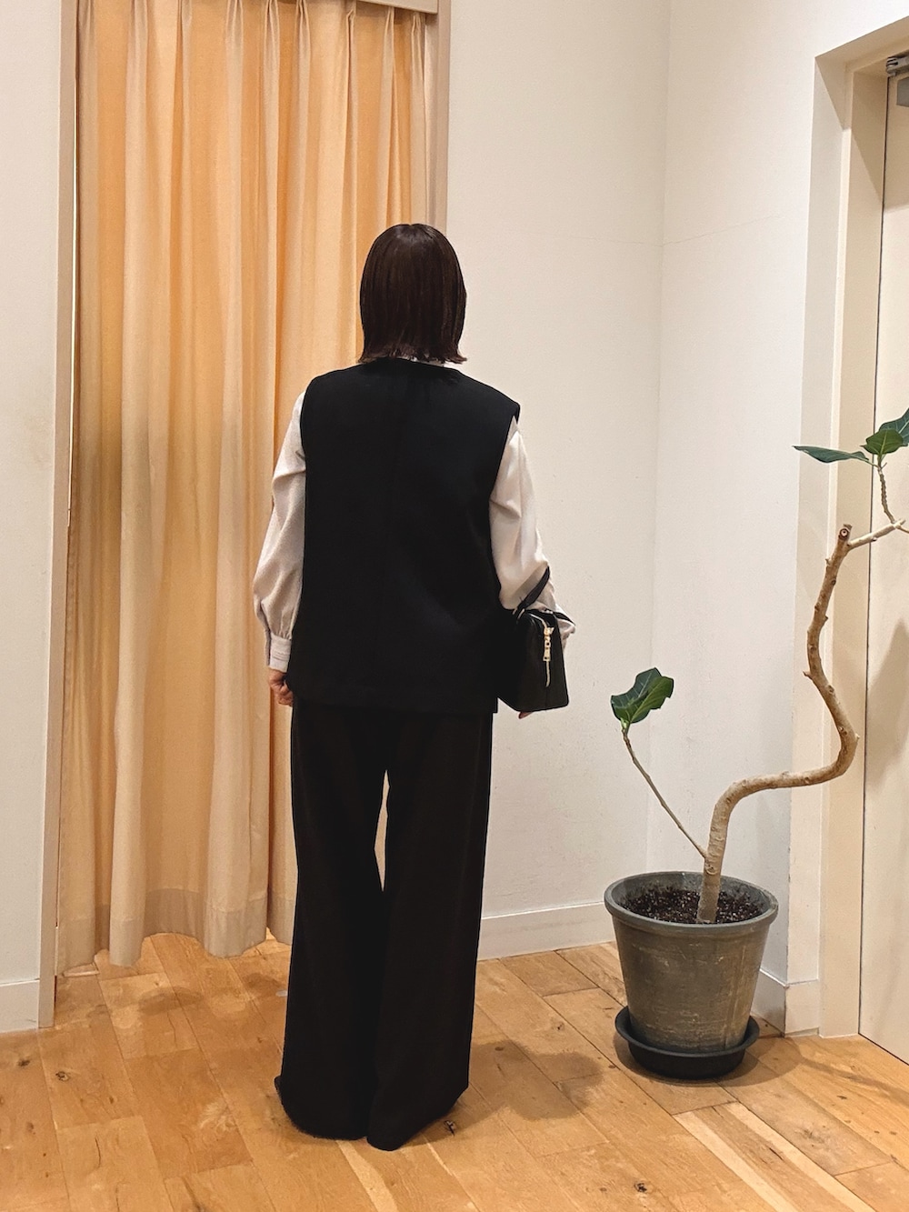 ブラック系のパンプス、ブラック系のハンドバッグ、ブラック系のベストを着用したレディースの秋コーディネートの2枚目の写真