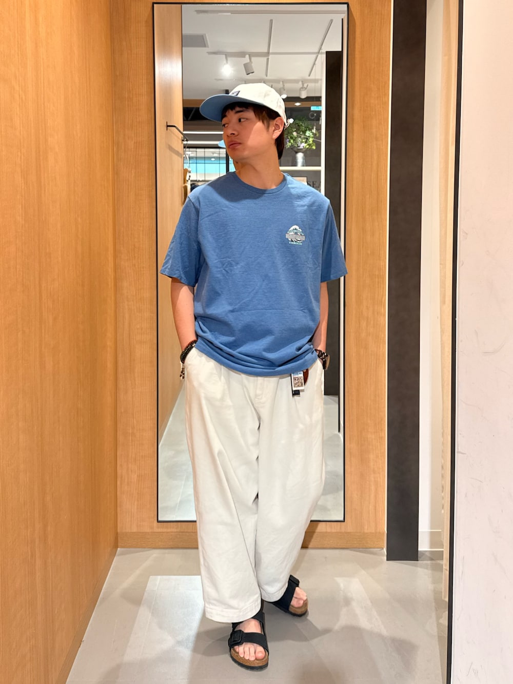 ブルー系のTシャツ/カットソー、ブラック系のサンダル、ホワイト系のキャップを着用したメンズの春コーディネートの2枚目の写真