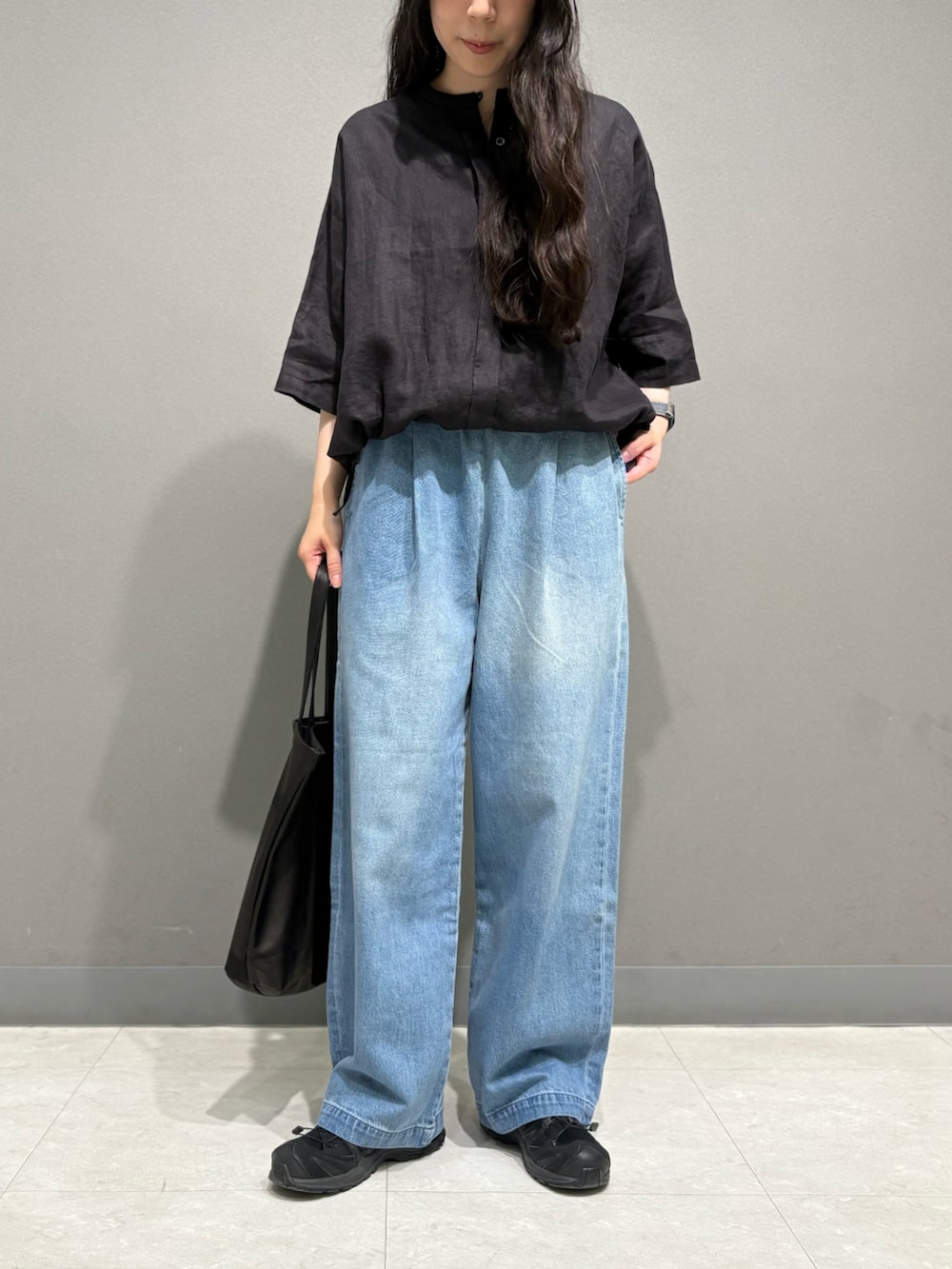ブラック系のシャツ/ブラウス、ブラック系のトートバッグ、ブルー系のデニムパンツを着用したレディースの夏コーディネートの2枚目の写真