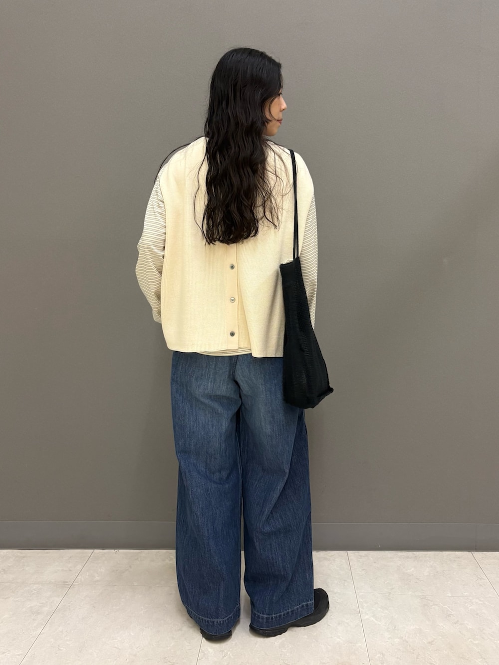 ホワイト系のベスト、ブルー系のデニムパンツ、ブラック系のトートバッグを着用したレディースの秋コーディネートの5枚目の写真