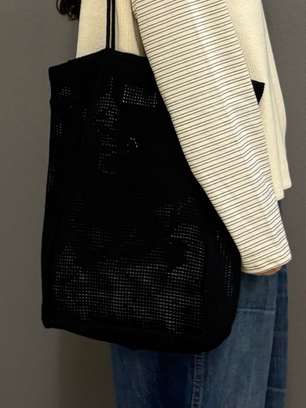 ホワイト系のベスト、ブルー系のデニムパンツ、ブラック系のトートバッグを着用したレディースの秋コーディネートの8枚目の写真