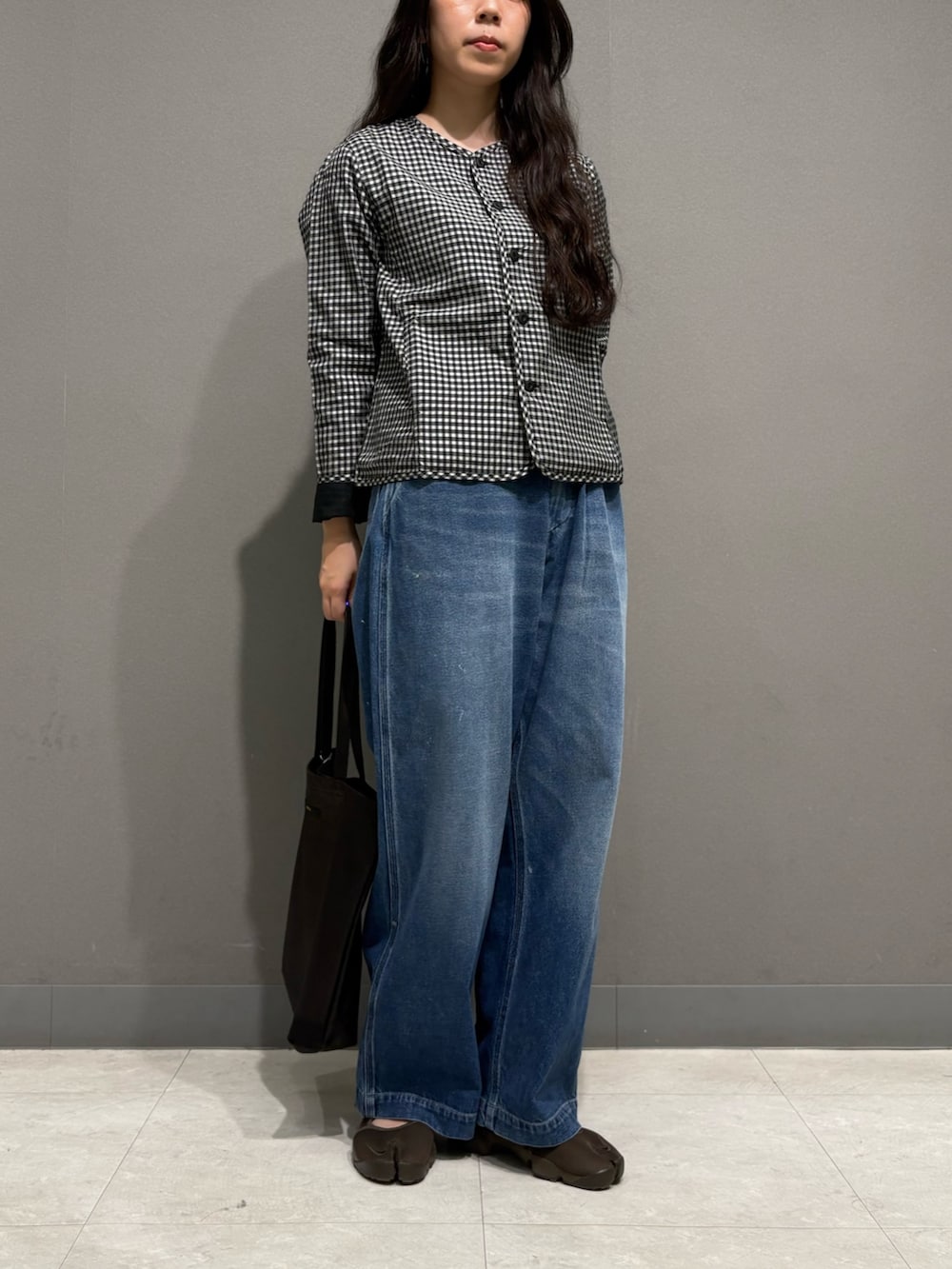 ブルー系のデニムパンツ、ブラック系のノーカラージャケット、ブラック系のトートバッグを着用したレディースの夏コーディネートの4枚目の写真
