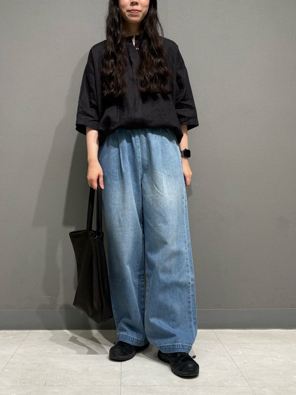 ブラック系のシャツ/ブラウス、ブラック系のトートバッグ、ブルー系のデニムパンツを着用したレディースの夏コーディネートの3枚目の写真