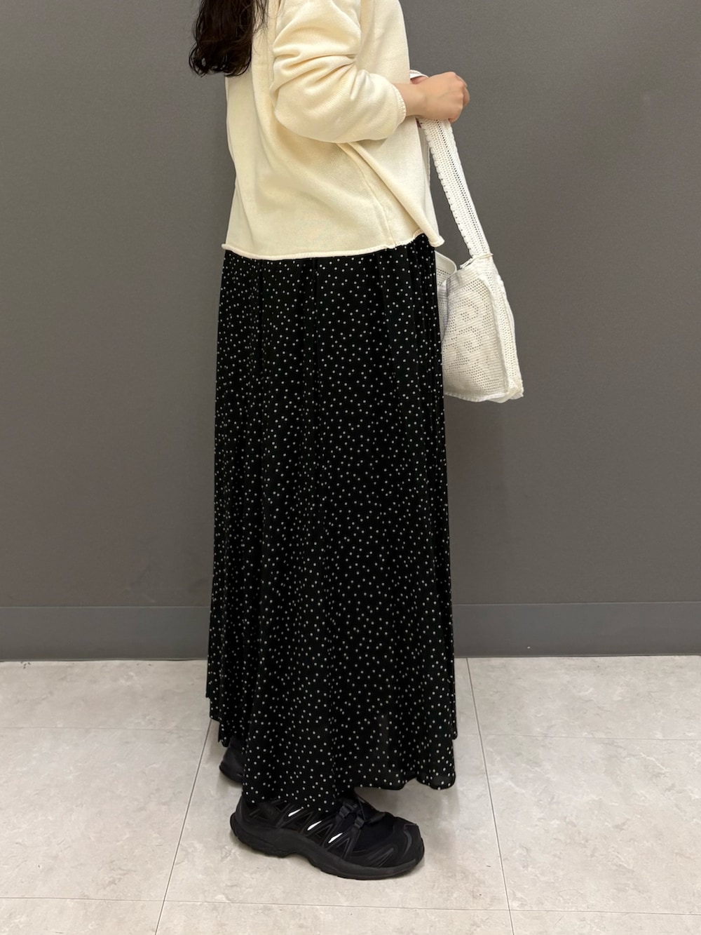 ホワイト系のニット/セーター、ホワイト系のTシャツ/カットソー、ブラック系のスカートを着用したレディースの秋コーディネートの7枚目の写真