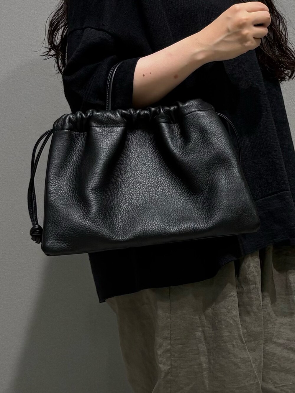 ベージュ系のその他パンツ、ブラック系のニット/セーター、ブラック系のその他雑貨を着用したレディースの夏コーディネートの6枚目の写真