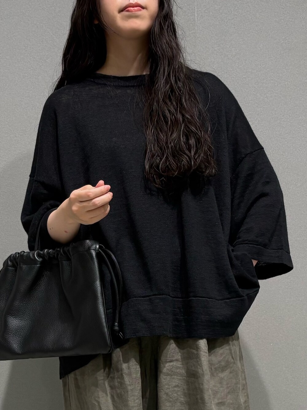 ベージュ系のその他パンツ、ブラック系のニット/セーター、ブラック系のその他雑貨を着用したレディースの夏コーディネートの2枚目の写真
