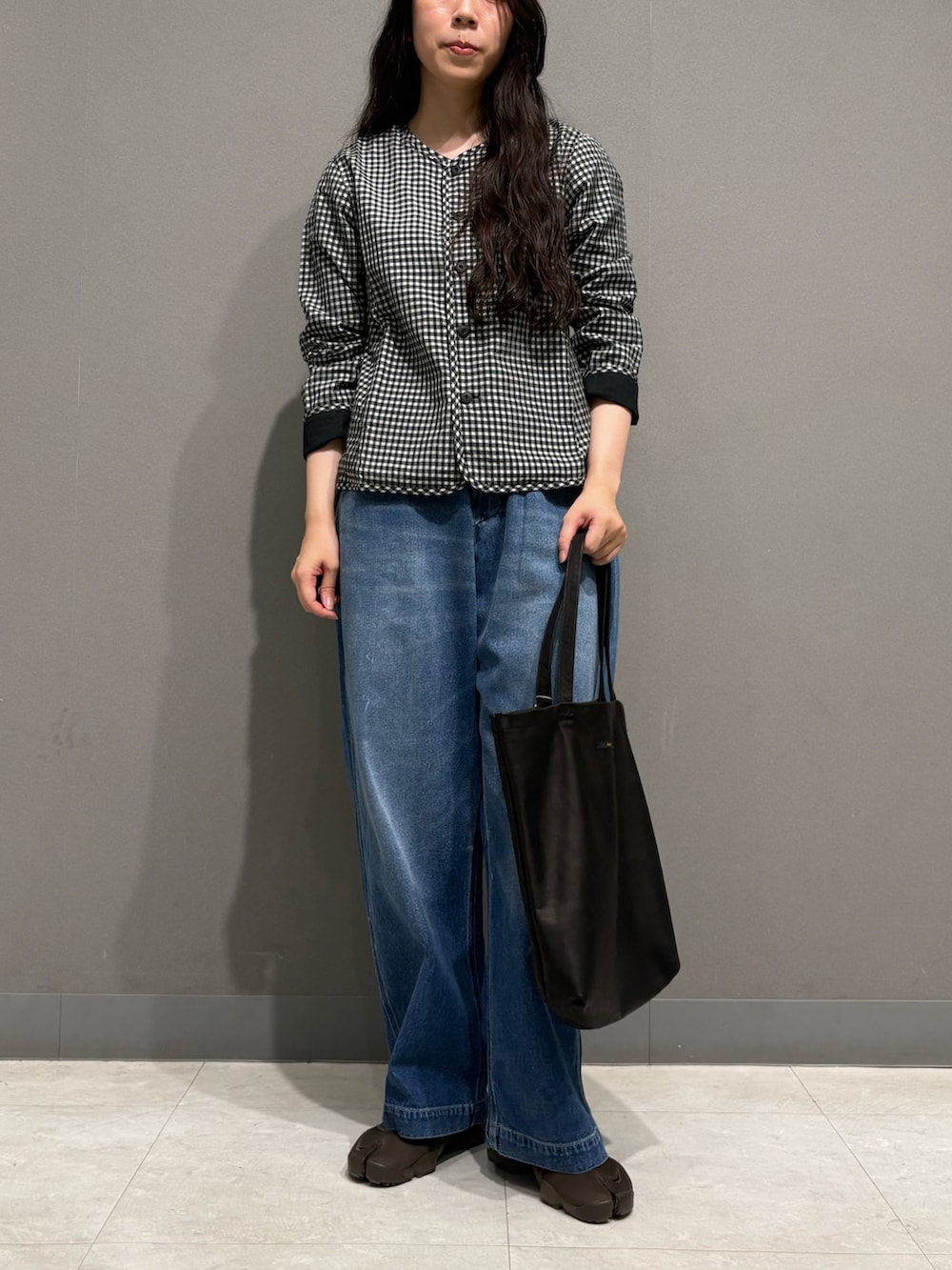 ブルー系のデニムパンツ、ブラック系のノーカラージャケット、ブラック系のトートバッグを着用したレディースの夏コーディネートの3枚目の写真
