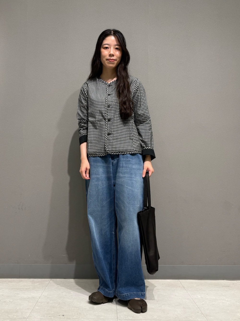 ブルー系のデニムパンツ、ブラック系のノーカラージャケット、ブラック系のトートバッグを着用したレディースの夏コーディネートの2枚目の写真