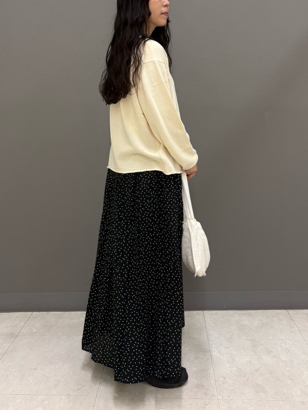 ホワイト系のニット/セーター、ホワイト系のTシャツ/カットソー、ブラック系のスカートを着用したレディースの秋コーディネートの5枚目の写真
