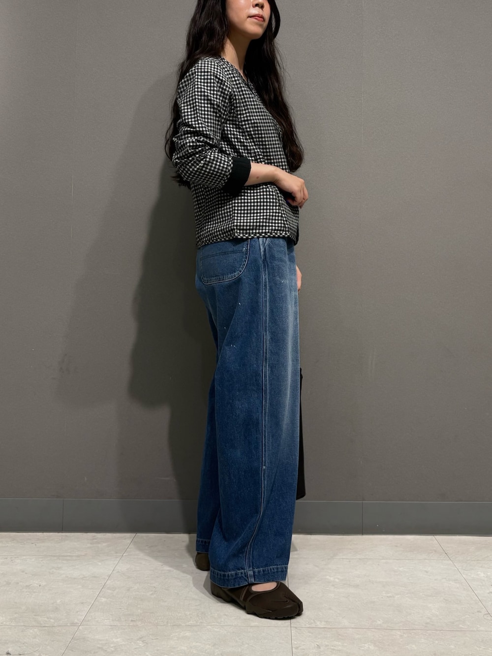 ブルー系のデニムパンツ、ブラック系のノーカラージャケット、ブラック系のトートバッグを着用したレディースの夏コーディネートの5枚目の写真