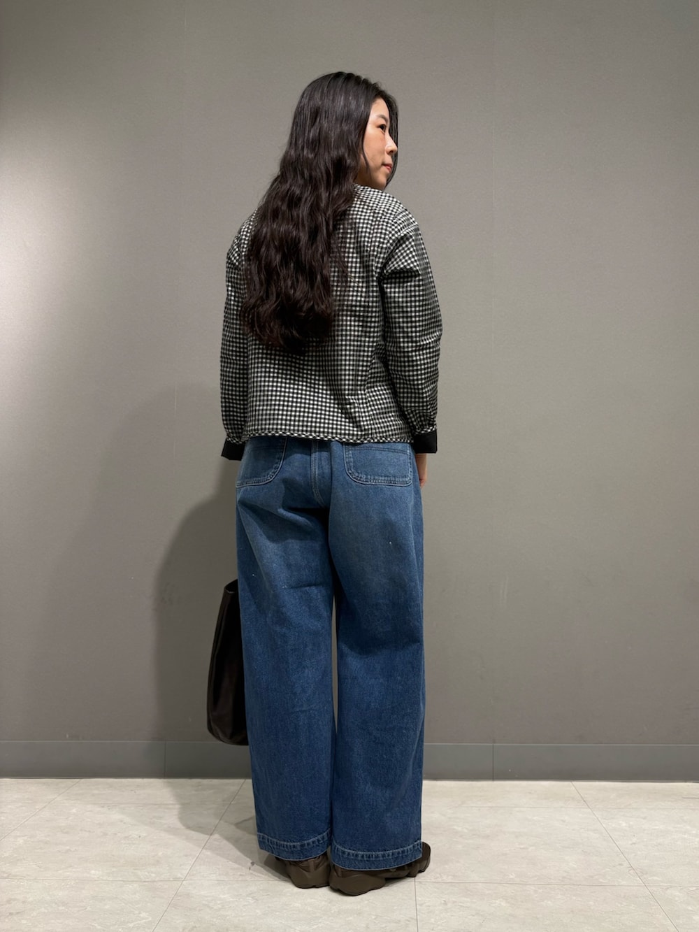 ブルー系のデニムパンツ、ブラック系のノーカラージャケット、ブラック系のトートバッグを着用したレディースの夏コーディネートの6枚目の写真