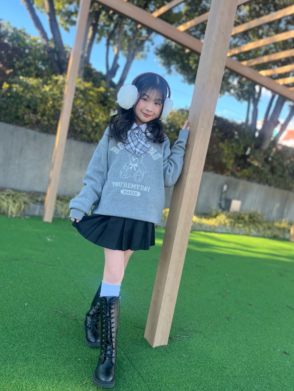 グレー系のニット/セーター、ブラック系のスカート、ブラック系のブーツを着用したキッズの春コーディネートの3枚目の写真