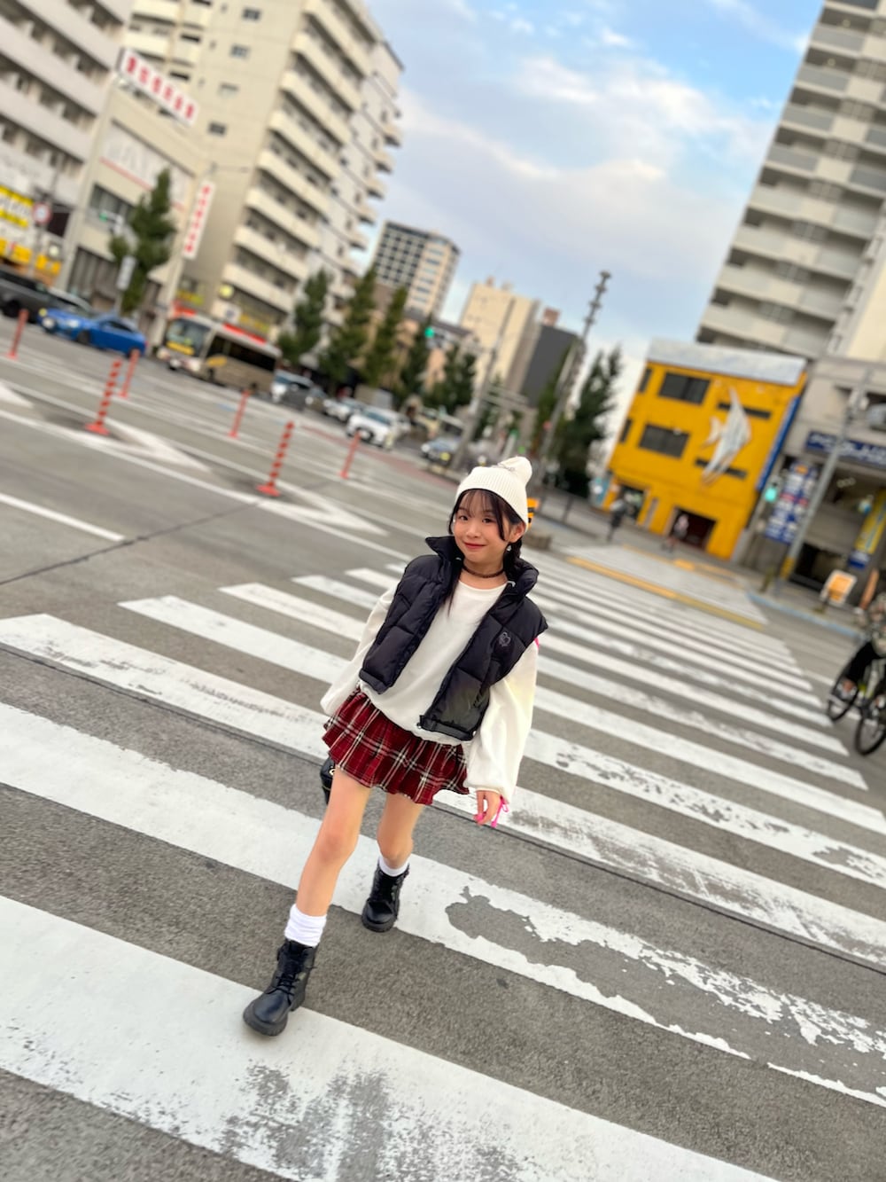 ブラック系のダウンベスト、レッド系のスカートを着用したキッズの秋コーディネートの2枚目の写真