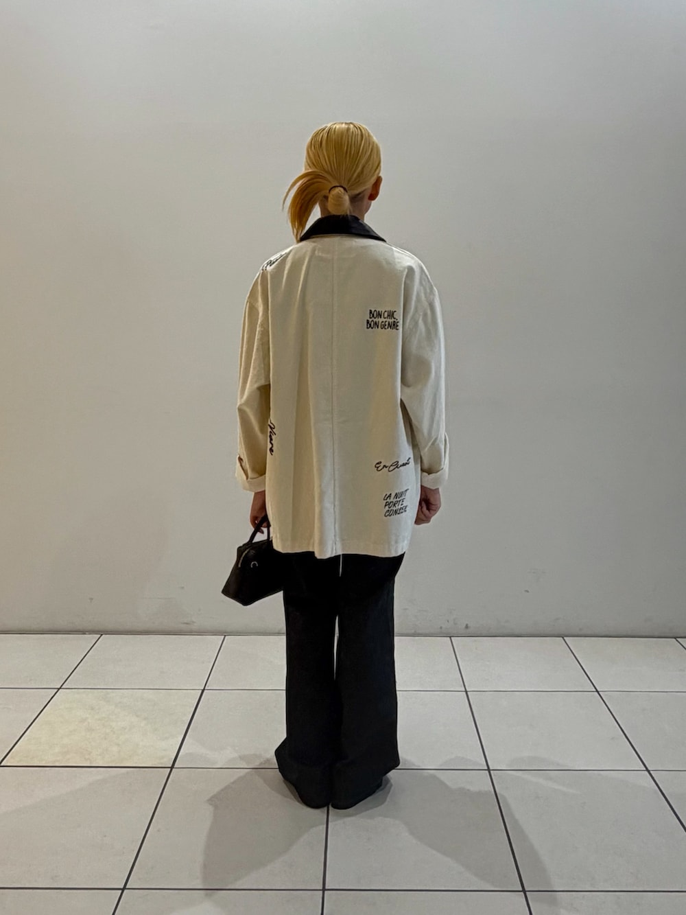 ブラック系のデニムパンツ、ブラック系のハンドバッグ、ブラック系のTシャツ/カットソーを着用したレディースの秋コーディネートの3枚目の写真