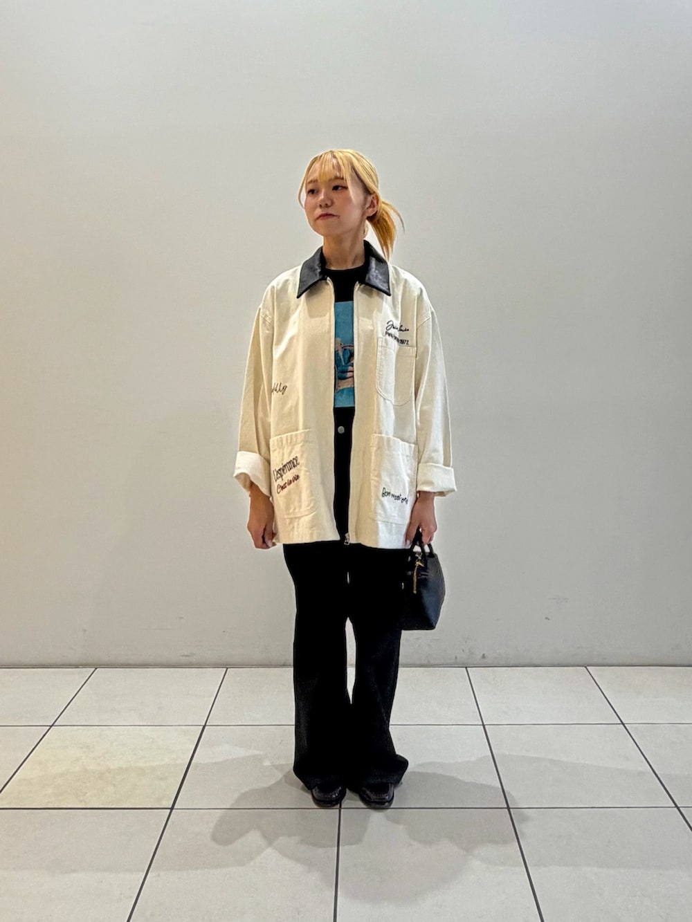 ブラック系のデニムパンツ、ブラック系のハンドバッグ、ブラック系のTシャツ/カットソーを着用したレディースの秋コーディネートの4枚目の写真