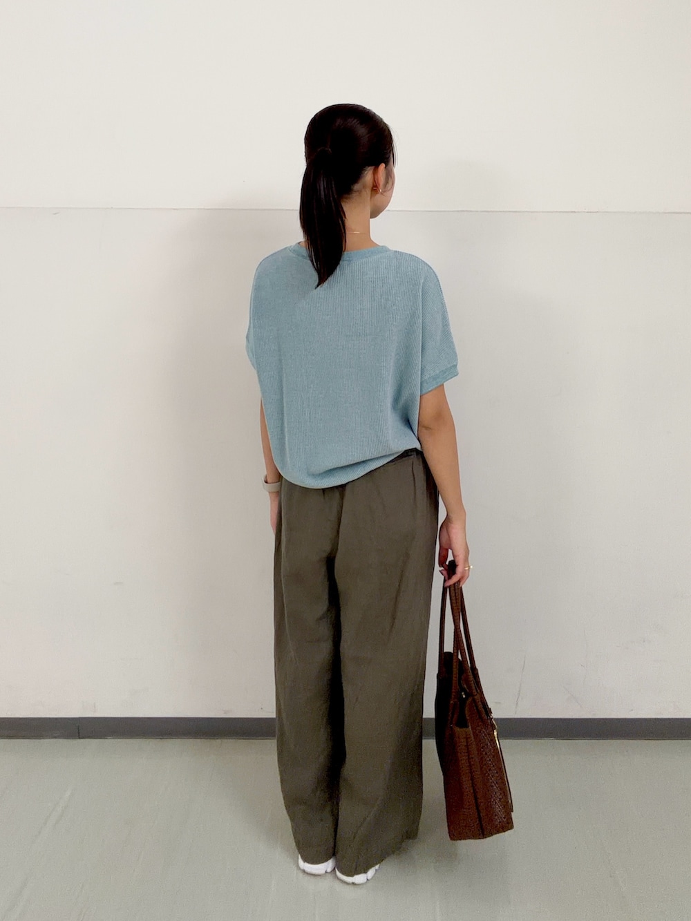 ブラウン系のトートバッグ、ブルー系のTシャツ/カットソー、ホワイト系のスニーカーを着用したレディースの春コーディネートの3枚目の写真