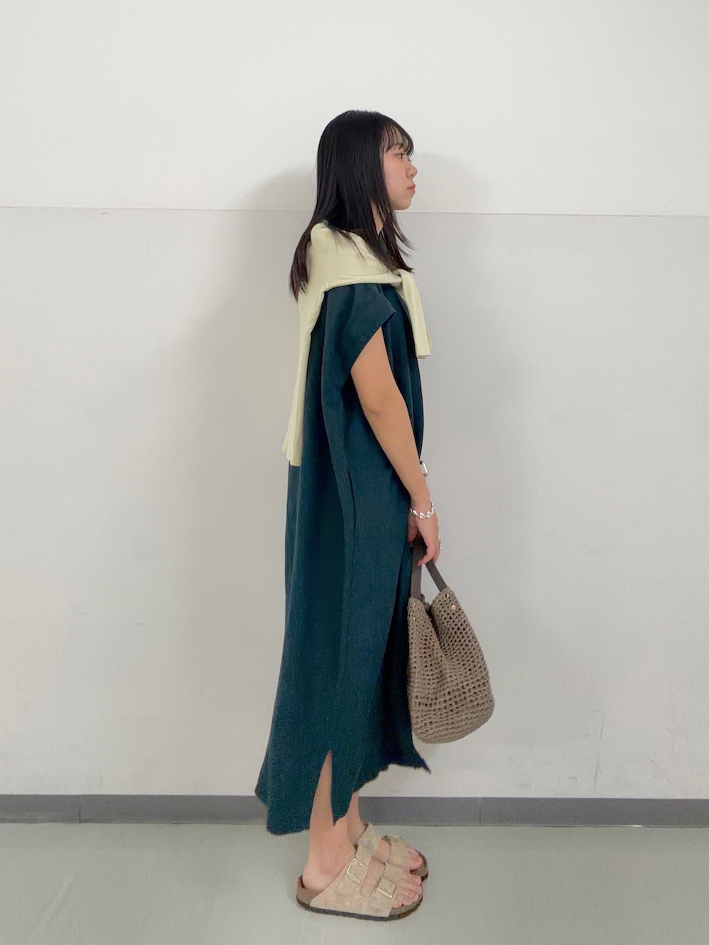 グリーン系のワンピース、イエロー系のカーディガン/ボレロ、ベージュ系のサンダルを着用したレディースの春コーディネートの3枚目の写真