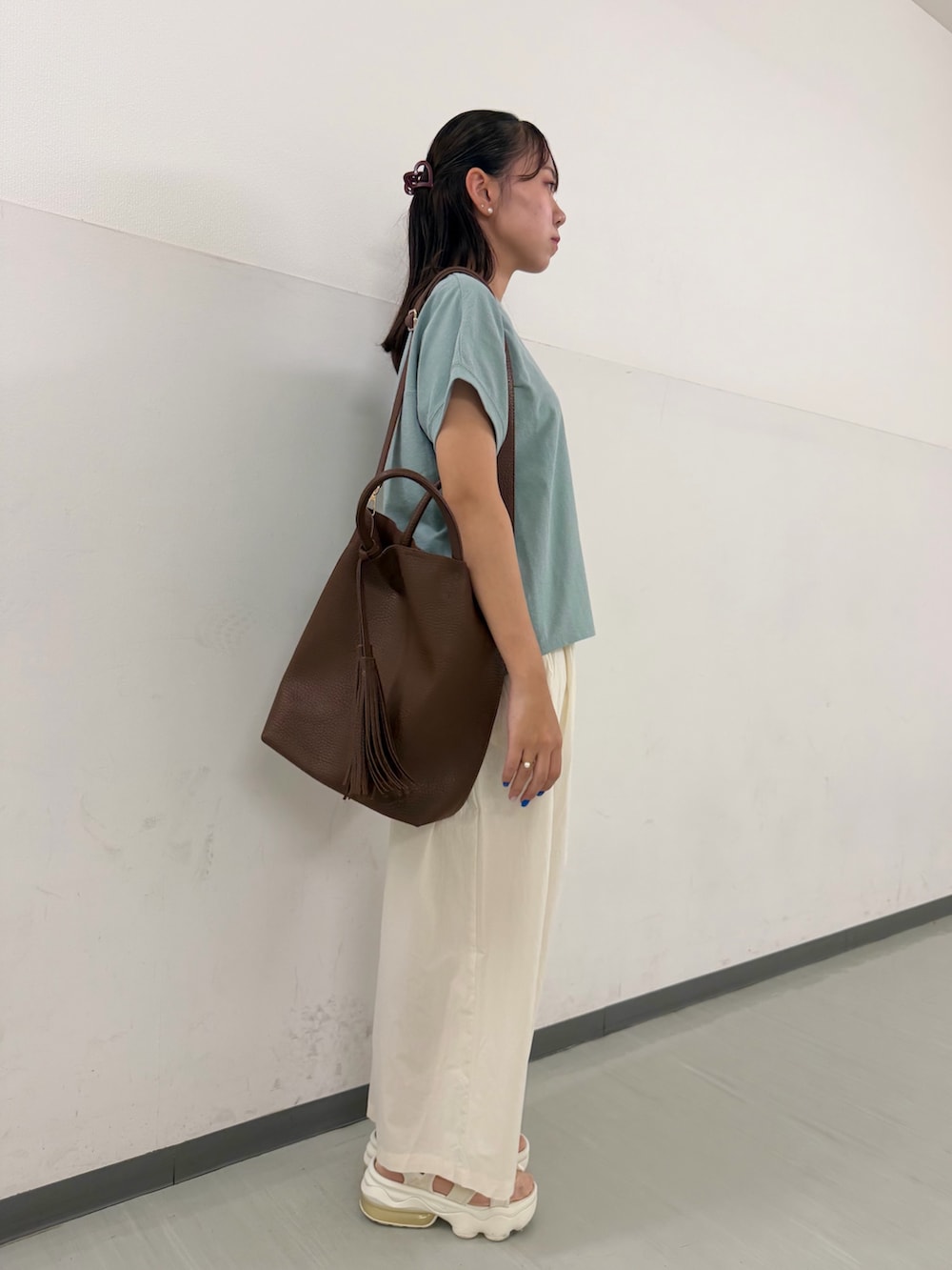 グリーン系のTシャツ/カットソー、ホワイト系のその他パンツ、ブラウン系のトートバッグを着用したレディースの夏コーディネートの2枚目の写真