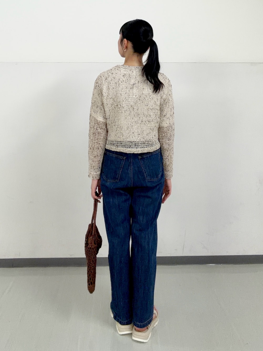 ブルー系のデニムパンツ、ホワイト系のTシャツ/カットソー、ホワイト系のサンダルを着用したレディースの春コーディネートの3枚目の写真