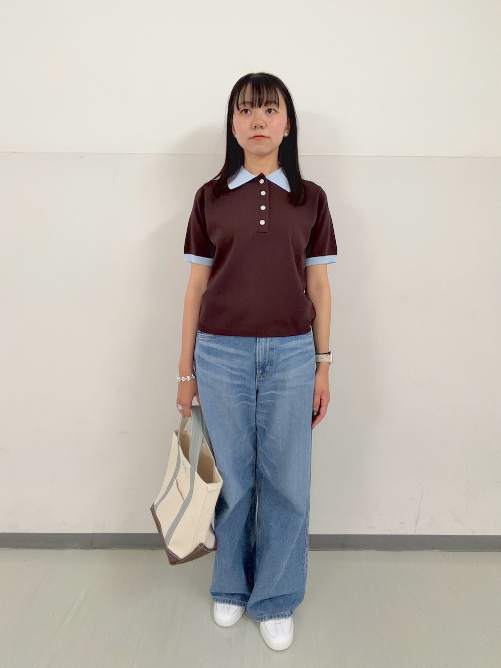 ブラウン系のニット/セーター、グリーン系のトートバッグ、ブルー系のデニムパンツを着用したレディースの春コーディネートの4枚目の写真