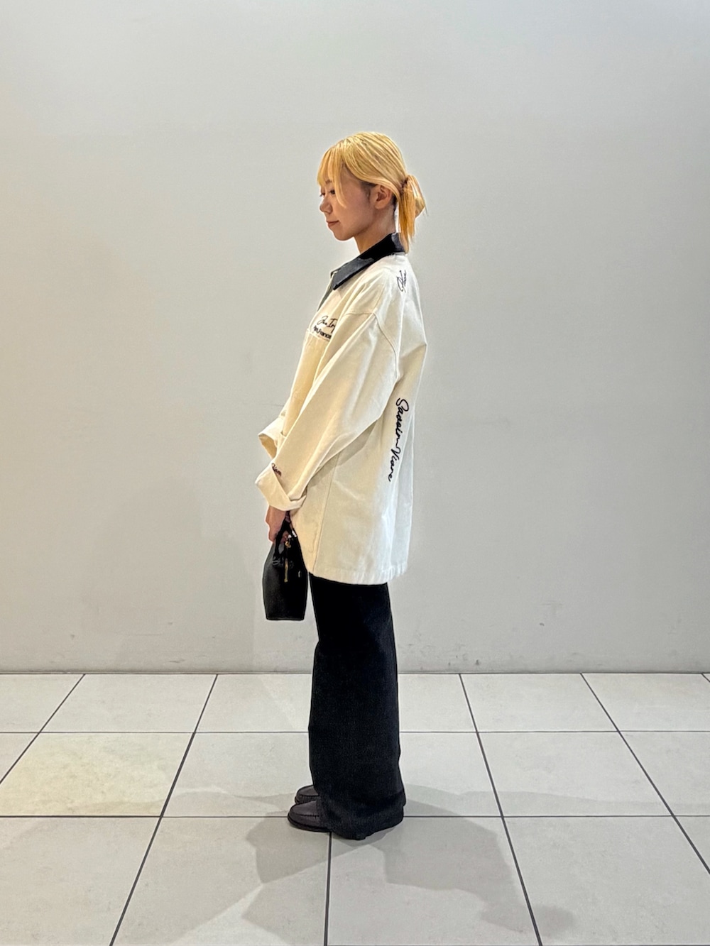 ブラック系のデニムパンツ、ブラック系のハンドバッグ、ブラック系のTシャツ/カットソーを着用したレディースの秋コーディネートの2枚目の写真