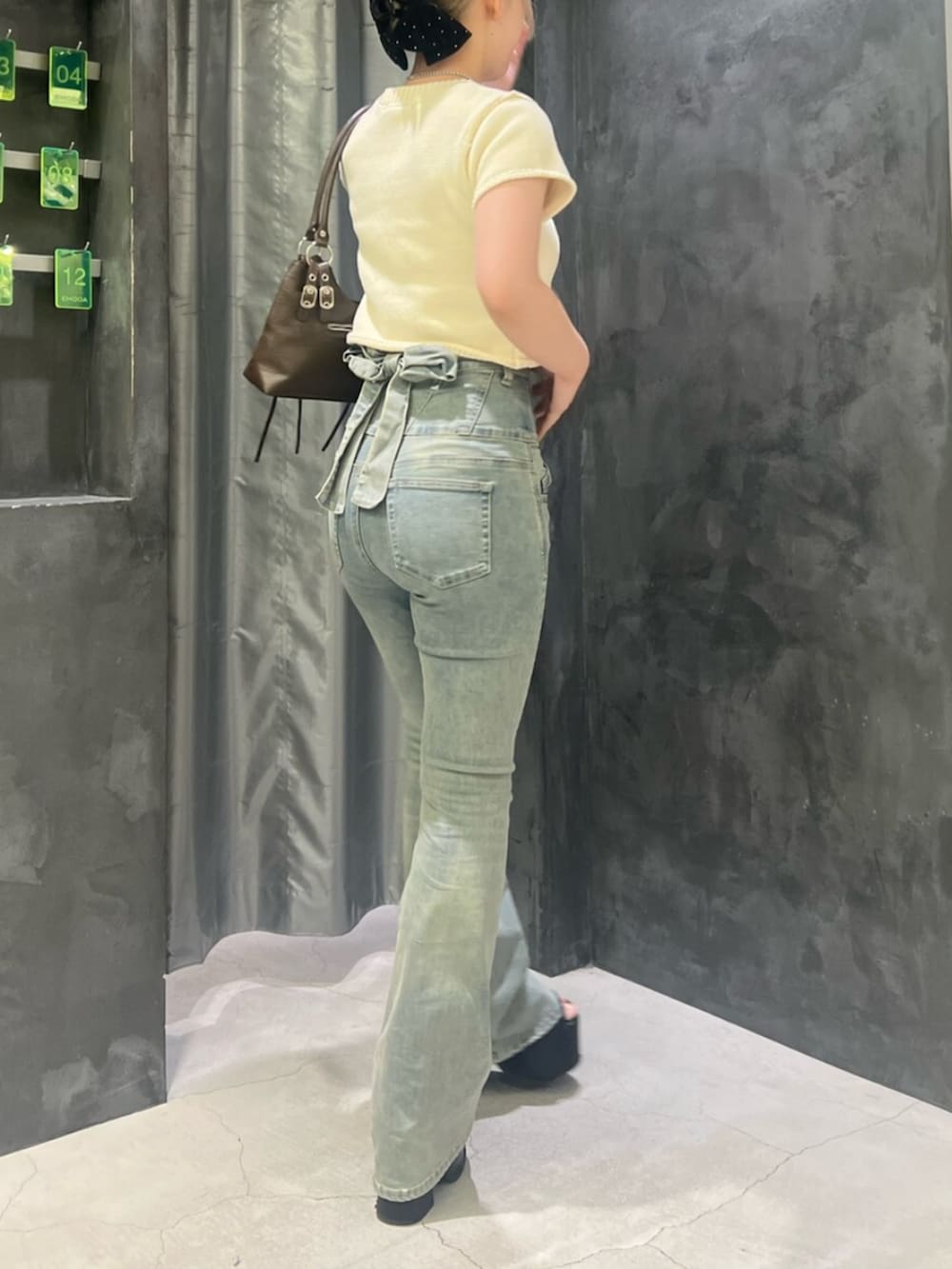 ブラック系のサンダル、ブルー系のデニムパンツ、ブラウン系のショルダーバッグを着用したレディースの夏コーディネートの3枚目の写真