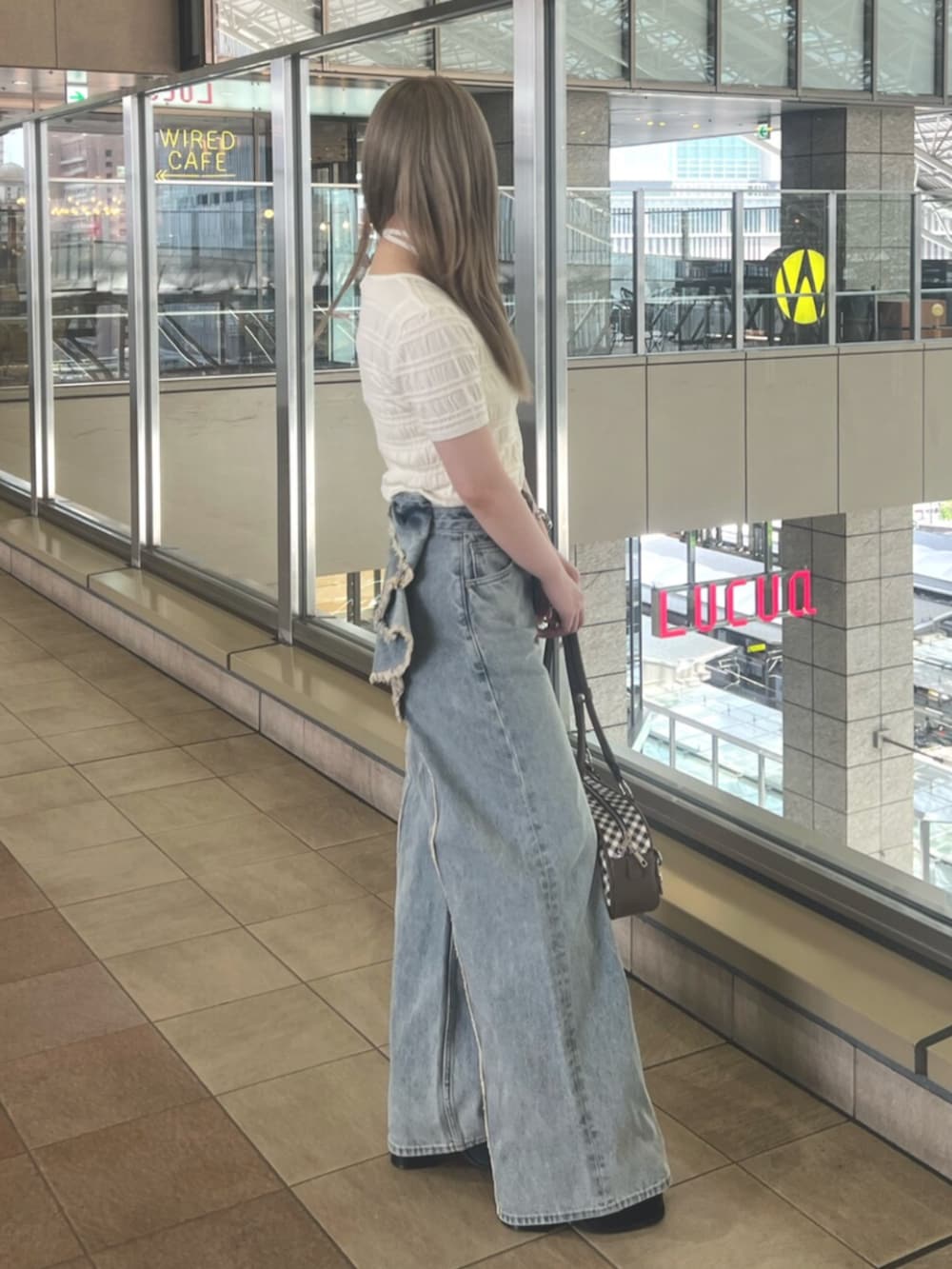 ホワイト系のニット/セーター、ブルー系のデニムパンツ、ブラウン系のハンドバッグを着用したレディースの春コーディネートの2枚目の写真