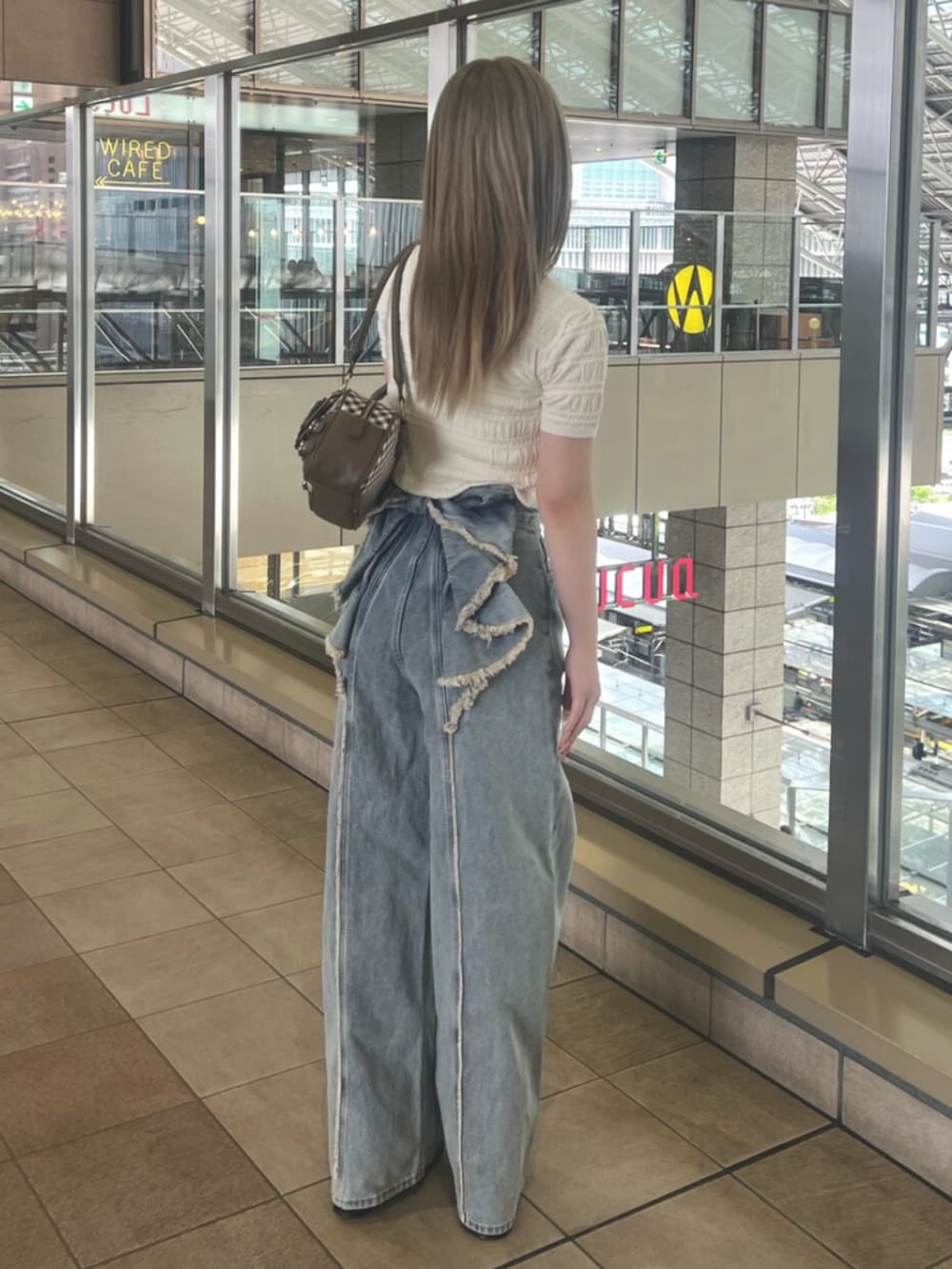 ホワイト系のニット/セーター、ブルー系のデニムパンツ、ブラウン系のハンドバッグを着用したレディースの春コーディネートの3枚目の写真