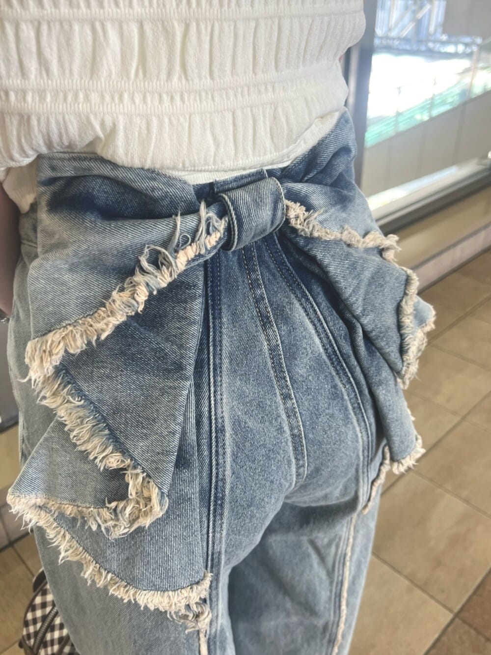 ホワイト系のニット/セーター、ブルー系のデニムパンツ、ブラウン系のハンドバッグを着用したレディースの春コーディネートの4枚目の写真