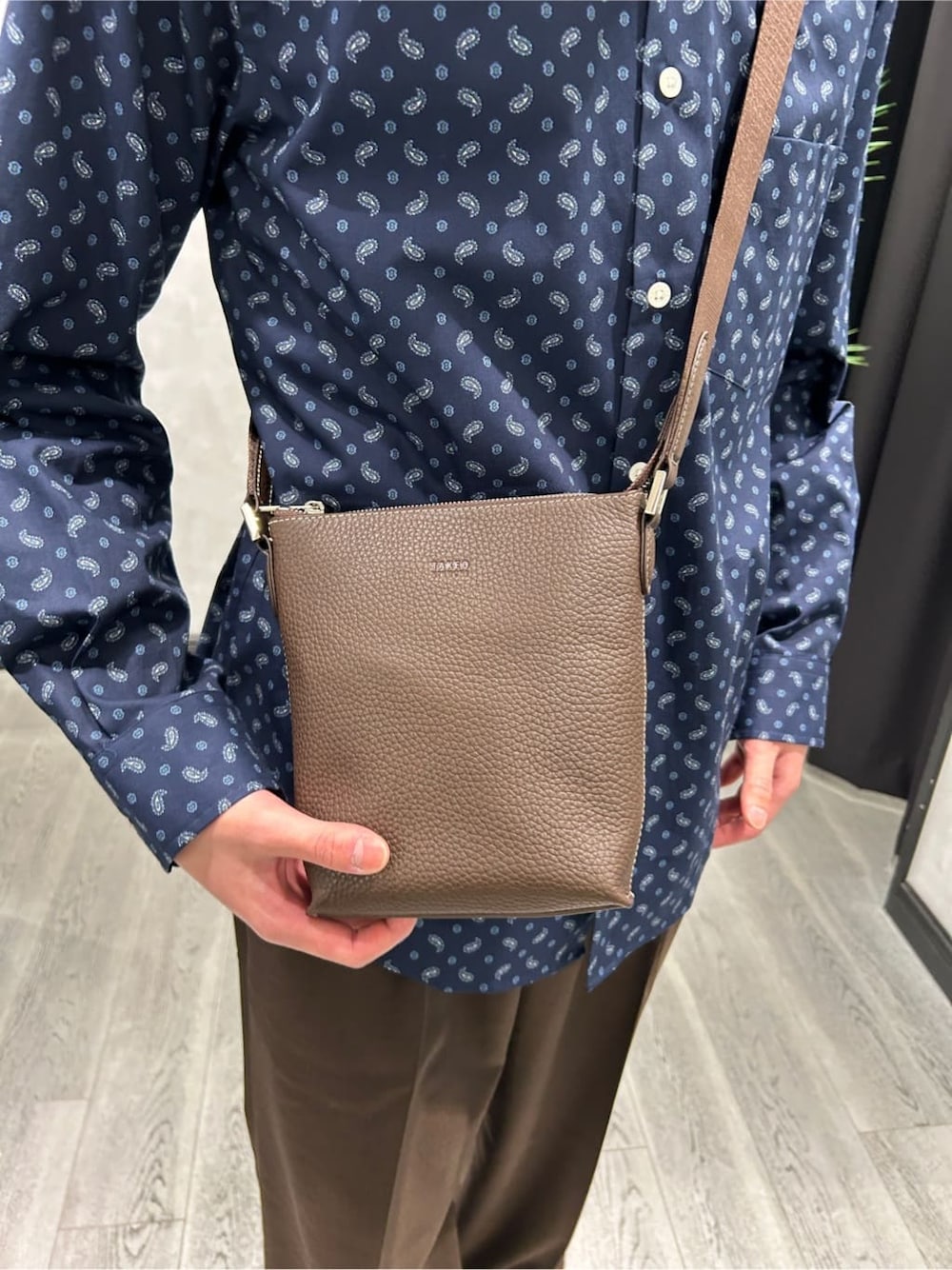 グレー系のカーディガン/ボレロ、ブルー系のシャツ/ブラウス、ブラウン系のスラックスを着用したメンズの春コーディネートの7枚目の写真